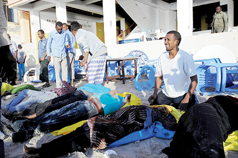 TOPSHOT - A Somali man cries next to dead bodies on the Lido beach on January 22, 2016 following an overnight attack on a beachfront restaurant in Mogadishu.  Somalia's Islamist Shebab militants killed at least 19 people when five gunmen detonated a bomb before storming a popular seaside restaurant in the capital Mogadishu, police said. / AFP / MOHAMED ABDIWAHAB