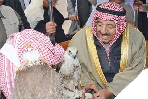 His Highness the Amir Sheikh Sabah Al-Ahmad Al-Jaber Al-Sabah interacts with a falconer attending the festival.