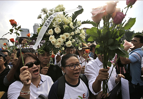 Activists hold flowers during a rally condemning Thursday's attack outside the Starbucks cafe where it took place in Jakarta, Indonesia, Friday, Jan. 15, 2016. Indonesians were shaken but refusing to be cowed a day after a deadly attack in a busy district of central Jakarta that has been claimed by the Islamic State group. (AP Photo/Dita Alangkara)