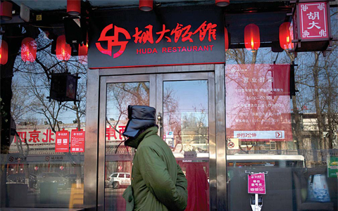 BEIJING: A man walks past a branch of the Hu Da hot pot restaurant chain. —AP