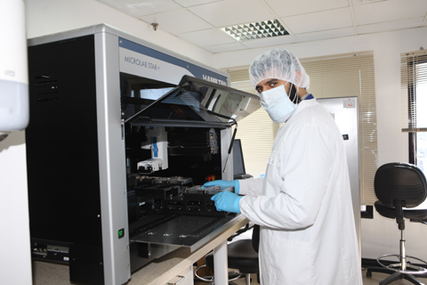 A lab technician works on a machine.