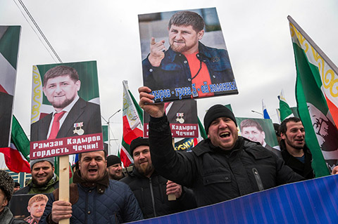 People shout slogans as they hold up images of the head of the Chechen republic Ramzan Kadyrov, during a rally in central Grozny, on January 22, 2016.   Tens of thousands of people flooded into the streets of Grozny, the capital of Russia's North Caucasus region of Chechnya, for a mass state-sponsored demonstration in support of strongman leader Ramzan Kadyrov. / AFP / ILIA VARLAMOV