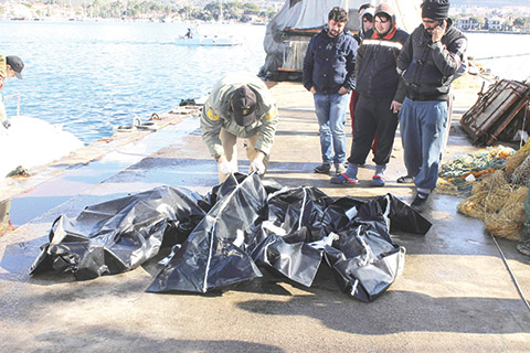 People check bodies of migrants that were drowned as they were trying to reach Greece, at a port near Izmir, Turkey, Thursday, Jan. 21, 2016. Turkey's coast guard says 12 migrants have drowned after a boat taking them to the Greek islands capsized in rough weather. About 40 migrants have died so far this year off Turkey's coast while trying to cross into Greece, the coast guard says. (IHA via AP) TURKEY OUT
