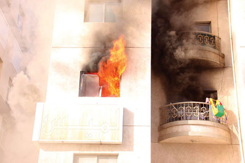 Flames come out of the window of a 3rd floor apartment in Jabriya.