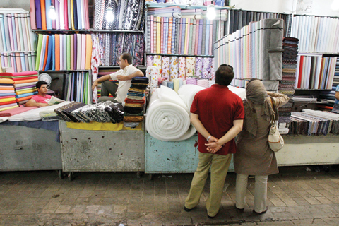 TEHRAN: In this July 14, 2012 file photo two potential Iranian customers look at fabric bolts in Tehran’s old main bazaar, Iran, as two merchants sit at left. — AP