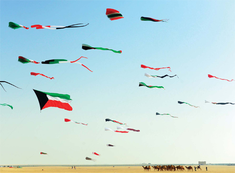 KUWAIT: Kites shaped as flags of Kuwait and Gulf states fly above a herd of camels in the Kuwaiti desert. — KUNA