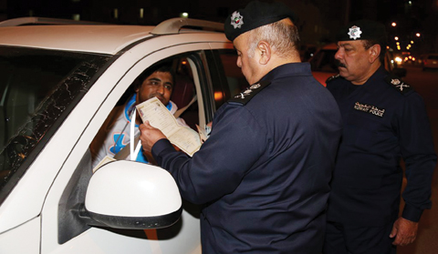 KUWAIT: Senior Interior Ministry officials inspect a driver’s papers during a crackdown in Mahboula Monday night.
