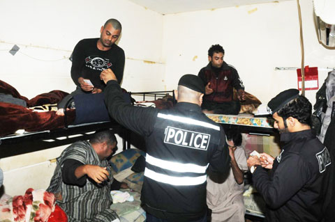 KUWAIT: Policemen check the documents of workers in their residence in Bneid Al-Gar yesterday. — KUNA