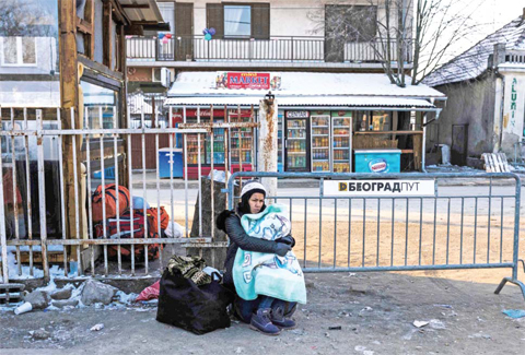 PRESEVO: A woman holds her baby as she waits with other migrants and refugees for a bus on January 20, 2016 at a registration camp in southern Serbian town of Presevo, after crossing the Macedonian border, as temperature fall to minus 15 Celsius. — AFP