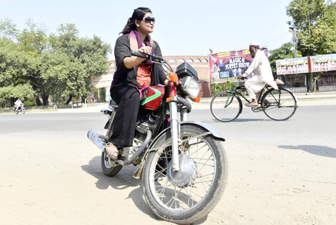 LAHORE: Pakistani housewife Hina Kazmi rides a motorcycle on a street. — AFP photos