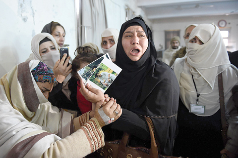 CHARSADDA, Pakistan : A relative of a 2014 Peshawar school attack victim shows her son’s pictures to a student victim (left) of the Bacha Khan University attack at a hospital in Charsadda yesterday. —AFP