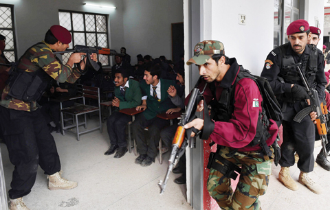 PESHAWAR: Pakistani Elite Police Force take part in a drill to fight against militants at a school in Peshawar yesterday. A Pakistan university attacked by the Taleban last week has demanded the government arm its staff as it seeks to boost security after the deadly assault in which 21 people were killed, officials said. — AFP