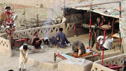 LAHORE: Members of a gypsy family cook food in their make-shift home in suburbs of Lahore, Pakistan yesterday. — AP