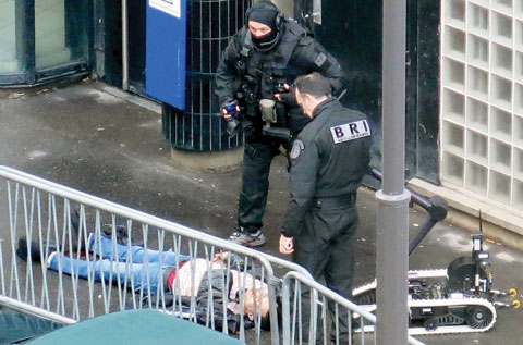 PARIS: Policemen stand by a man shot dead in front of a police station yesterday in Paris. French police shot dead a knife-wielding man yesterday as he attacked a police station in Paris, a year to the day since jihadist gunmen killed 12 people at Charlie Hebdo newspaper. — AFP