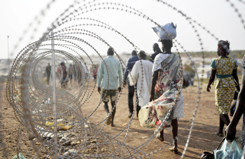 JUBA: Displaced people walk next to a razor wire fence at the United Nations base in the capital Juba, South Sudan. When a delegation of South Sudanese rebels returned to the government-controlled capital Juba last month after two years of war, many refugees thought they would finally return to the homes they fled.— AP