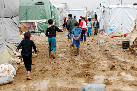 BEKAA VALLEY: Syrian refugee children walk in mud after a heavy rain at a refugee camp in the town of Hosh Hareem. — AP