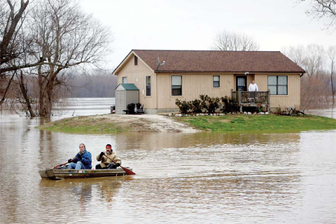 KIMMSWICK: Scott Fox, front, who decided it was time to leave his residence on Mississippi Boulevard, which was surrounded by water, paddles a boat with his friend Tony Watkins. —AP