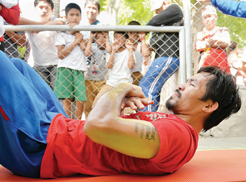 This photo taken on February 16, 2016 shows schoolchildren watching as Philippine boxing icon Manny Pacquiao works out during a training session at a sports complex in General Santos. —AFP