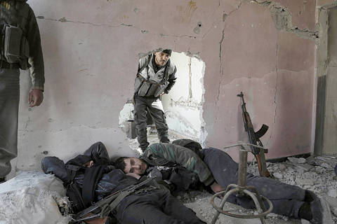 BALA, Syria: Syrian rebel fighters from the Failaq al-Rahman brigade take a break as they hide inside a building on the frontline against regime forces in this rebel-controlled village in the eastern Ghouta region, on the outskirts of the capital Damascus, yesterday. —AFP