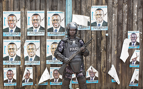 KAMPALA: A Ugandan riot policeman blocks the gate of the party headquarters of opposition leader Kizza Besigye, shortly after raiding the premises for the second time in a week, in the capital Kampala yesterday. —AP