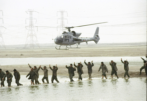 FILE - In this Monday, February 25, 1991 file photo, a Kuwaiti military helicopter herds Iraqi prisoners, arms in the air, across a stream in southeastern Kuwait, as Operation Desert Storm continues. Official sources reported the number of Iraqi troops surrendering at 18,000 - and growing.