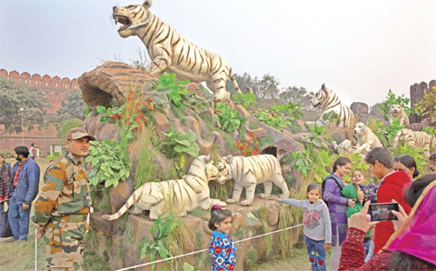 NEW DELHI: An Indian Army soldier stands guard as children get their photographs taken in front of the Republic Day Tableau of Indian state of Madhya Pradesh depicting models of white tigers at the Red Fort grounds, in New Delhi. — AP