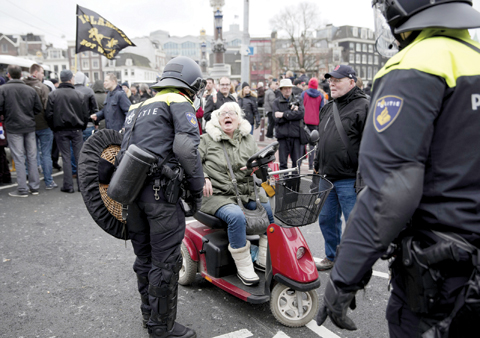 A woman jokes with Dutch riot police during a Pegida demonstration against immigration and islamization of Europe, in Amsterdam, Netherlands yesterday. — AP