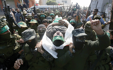 AL-MOGHRAGA: Palestinian members of the Ezzedine Al-Qassam Brigades, the armed wing of the Hamas movement carry the body of fellow militant Ahmed Al-Zahar during his funeral in the village of Al-Moghraga near the Nuseirat refugee camp in the central Gaza Strip yesterday. —AFP