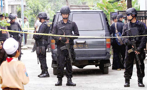 MALANG: Indonesian police officers stand guard outside the house of a suspected militant following a raid in Malang yesterday. — AP