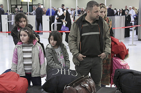 BAGHDAD: An Iraqi family returning from Europe waits for their luggage at Baghdad International Airport yesterday. —AP