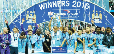 LONDON: Manchester City’s Belgian defender Vincent Kompany (center) holds up the League Cup surrounded by his team-mates during the presentation after Manchester City won the penalty shoot-out to win the English League Cup final football match between Liverpool and Manchester City at Wembley Stadium yesterday. — AFP