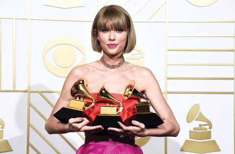 Taylor Swift poses in the press room with the awards for album of the year for 1989, pop vocal album for 1989 and best music video for ‘Bad Blood’.