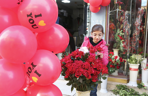 QAMISHLI: A Syrian girl arranges flowers at a shop displaying Valentine’s Day gifts. —AFP