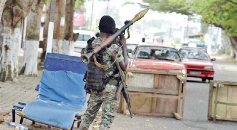 GRAND-BASSAM: An Ivorian soldier holds a Rocket-propelled grenade while manning a position in a street near the the Etoile du Sud hotel in Grand Bassam on Monday. — AFP