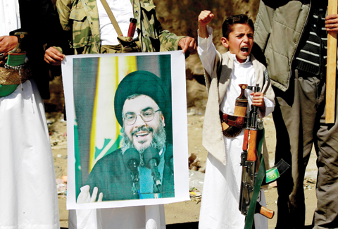 SANAA: A Yemeni boy shouts slogans as Houthi militiamen hold a poster depicting Lebanon’s Hezbollah chief Hassan Nasrallah during a gathering to show their support to Hezbollah following the Gulf states’ announcement declaring the group a “ terrorist organization”, in the capital Sanaa yesterday. — AFP