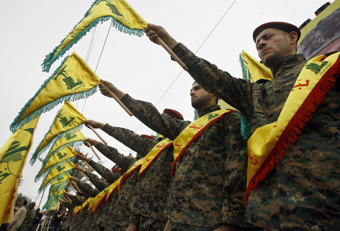Hezbollah fighters hold flags as they attend the funeral procession in this southern village yesterday of Hezbollah senior commander Ali Fayyad, who was killed last week during an offensive by Syrian troops and Hezbollah fighters in Syria,. Gulf nations formally branded Hezbollah a terrorist organization yesterday, ramping up the pressure on the Lebanese group. – AP