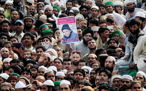 RAWALPINDI: People hold the photo of police officer Mumtaz Qadri, the convicted killer of a former governor, during his funeral, in Rawalpindi yesterday. — AP