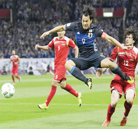 Japan’s Shinji Okazaki, center, leaps to control the ball against Syria’s Omar Midani (12) and Ahammad Kalasi (5) during their World Cup qualifying match in Saitama, north of Tokyo, yesterday. Japan defeated Syria. — AP