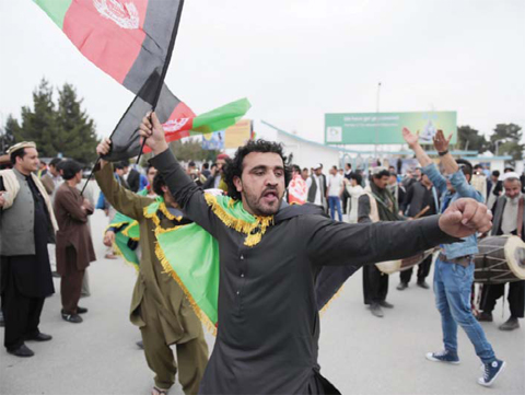Afghan cricket fans dance and wave the national flag as they welcome the country’s cricket team home at Kabul International Airport in Kabul