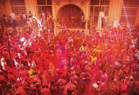 NEW DELHI: Indian Hindu widows throw flower petals during Holi celebrations at the Gopinath temple yesterday. —AP