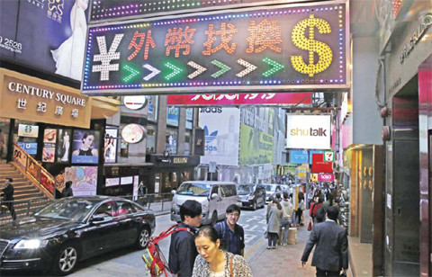 People walk beneath a sign for foreign currency exchange in Hong Kong