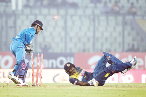 DHAKA: India’s captain Mahendra Singh Dhoni (left) breaks the stumps successfully as Sri Lanka’s Thisara Perera falls during the Asia Cup T20 cricket tournament match between India and Sri Lanka at the Sher-e-Bangla National Cricket Stadium in Dhaka yesterday. - AFP 