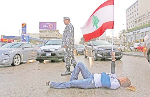 BEIRUT: A Lebanese demonstrator lies holding her national flag blocking the Dawra road, a major highway leading towards Beirut - slowing down rush hour traffic, in protest after authorities said they would reopen a landfill to ease an eight-month rubbish crisis. — AFP