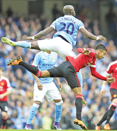 MANCHESTER: Manchester City's Eliaquim Mangala, top, and United's Jesse Lingard challenge for the ball during the English Premier League soccer match between Manchester City and Manchester United at the Etihad stadium in Manchester, yesterday. - AP