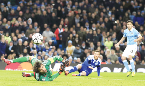 MANCHESTER: Kiev’s goalkeeper Oleksandr Shovkovskiy (left) dives as he watches a shot from Manchester City’s Jesus Navas (right) go past him, but it hits the post, during the Champions League round of 16 second leg soccer match between Manchester City and Dynamo Kiev at the Etihad Stadium yesterday. - AP n
