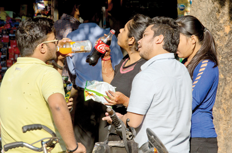 NEW DELHI: Indian teenagers eat and drink outside a street food stall yesterday. — AP photo