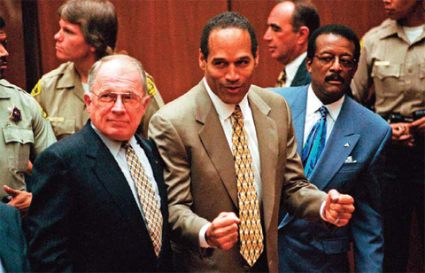 In this Oct3, 1995 file photo, OJ Simpson, center, reacts as he is found not guilty of murdering his ex-wife Nicole Brown and her friend Ron Goldman, as members of his defense team, F Lee Bailey, left, and Johnnie Cochran Jr, right, look on, in court.