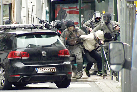 BRUSSELS: Armed police officers escort Salah Abdeslam to a police vehicle during a raid in the Molenbeek neighborhood of Brussels, Belgium on Friday March 18, 2016. The identity of Salah Abdeslam is confirmed yesterday, by French police and deputy mayor of Molenbeek, Ahmed El Khannouss quoting official Belgium police sources. —AP