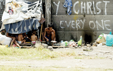 MANILA: A family eats their lunch beside a railway line in Manila. The country has a population well over 100 million with about 25 percent living in poverty. — AFP