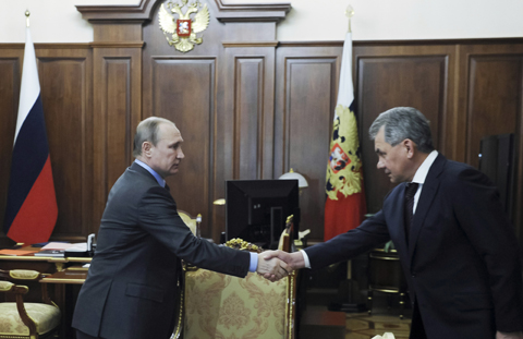 Russian President Vladimir Putin, left, shakes hands with Russian Defense Minister Sergey Shoygu during their meeting in the Kremlin in Moscow, Russia